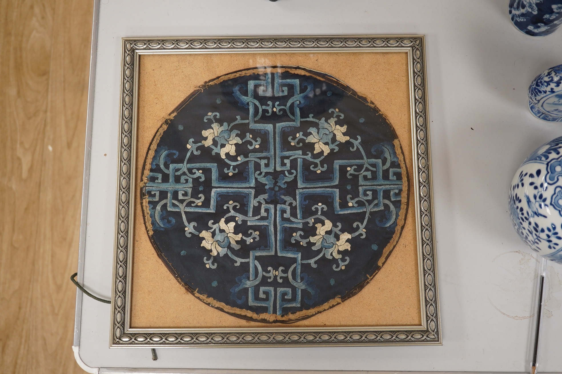 A framed 19th century Chinese silk embroidered floral roundel, possibly from a robe, 28cm diameter. Condition - main body of embroidery good, edging missing